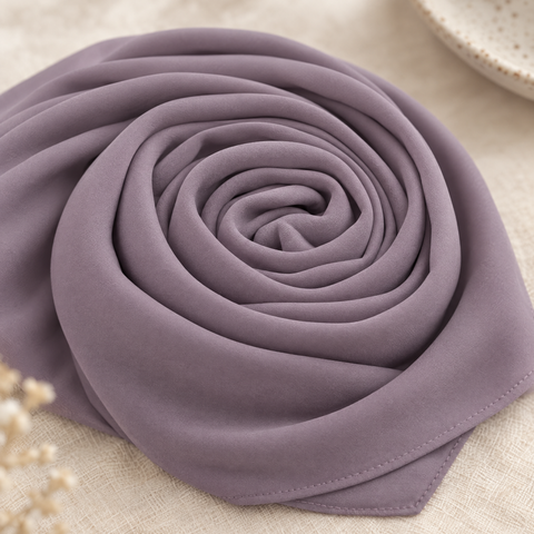 Bawal warna Lavender tergulung rapi di atas kain linen